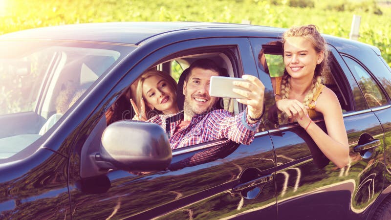 Happy young friends taking selfie while traveling together by car at countryside royalty free stock photography Happy young friends taking selfie while traveling together by car at countryside royalty free stock photography