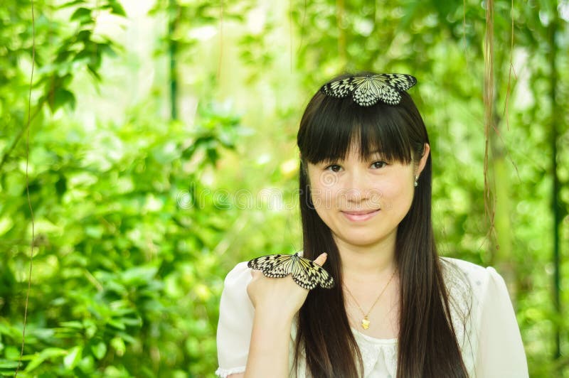 Happy young girl playing with butterfly in garden