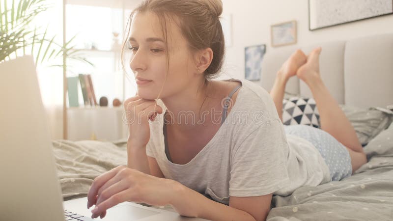 Happy young girl sitting on bed using smartphone and laptop at home. royalty free stock photo Happy young girl sitting on bed using smartphone and laptop at home. royalty free stock photo
