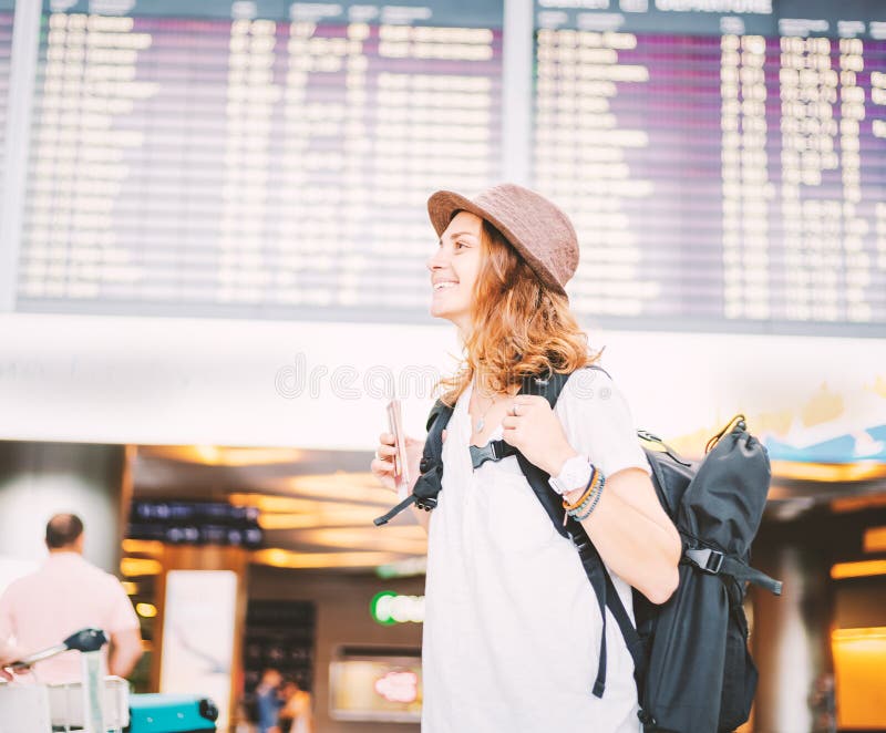 Happy young girl traveler at the airport with a backpack on the background of a departures board stock photography Happy young girl traveler at the airport with a backpack on the background of a departures board stock photography