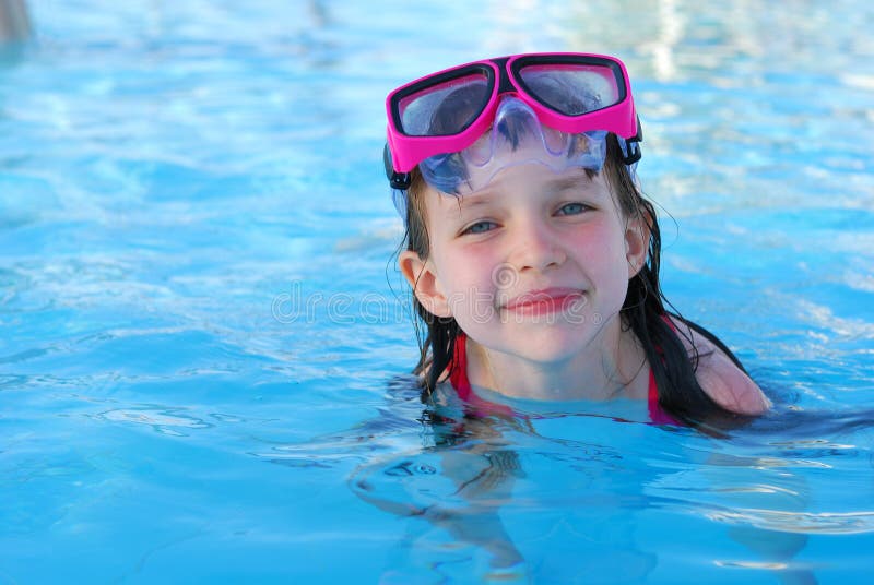 Smiling young girl swimming in a pool, wearing goggles. Smiling young girl swimming in a pool, wearing goggles.