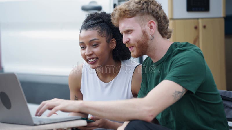 Interracial couple using laptop computer outdoors stock footage