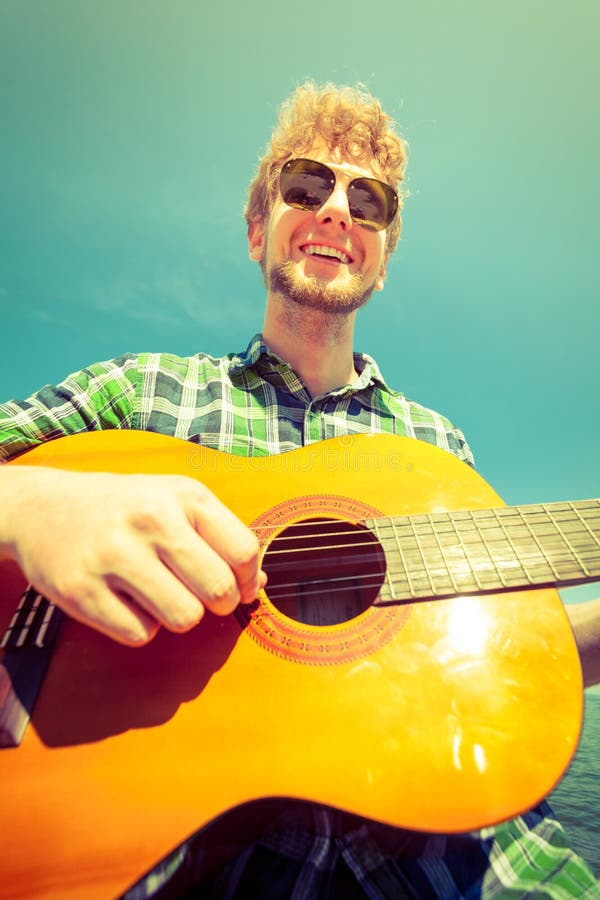 Happy young man hipster playing guitar.