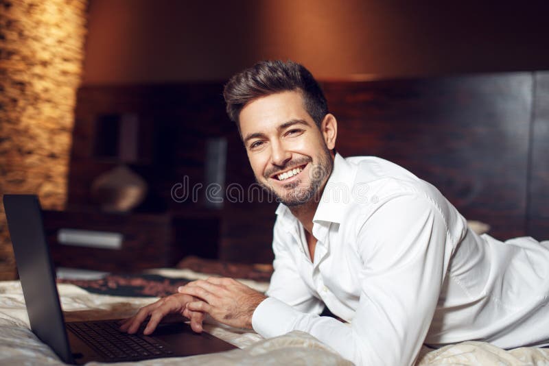 Happy young man smile with laptop in bed