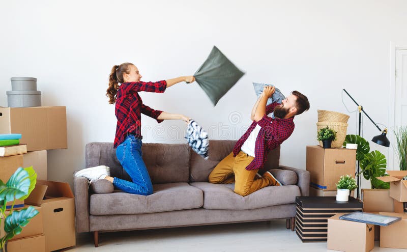 Happy young married couple moves to new apartment and laughing, jump, fight pillows stock images Happy young married couple moves to new apartment and laughing, jump, fight pillows stock images
