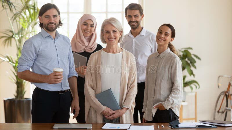 Happy multicultural team with old leader stand look at camera