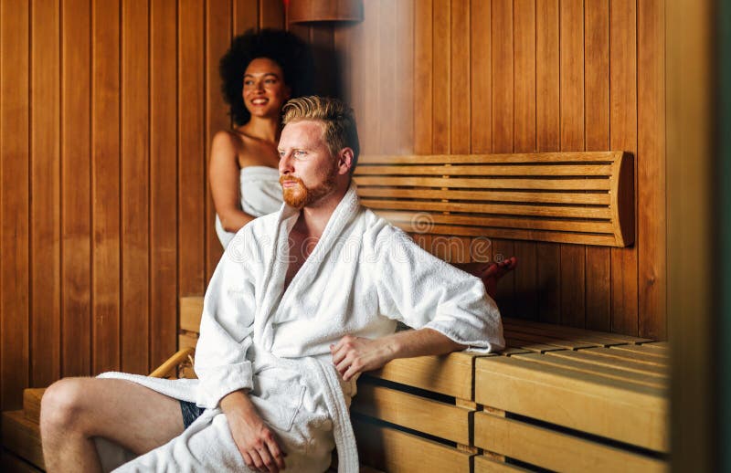 Happy young multiethnic couple enjoying a sauna at a spa resort on wellness weekend royalty free stock image