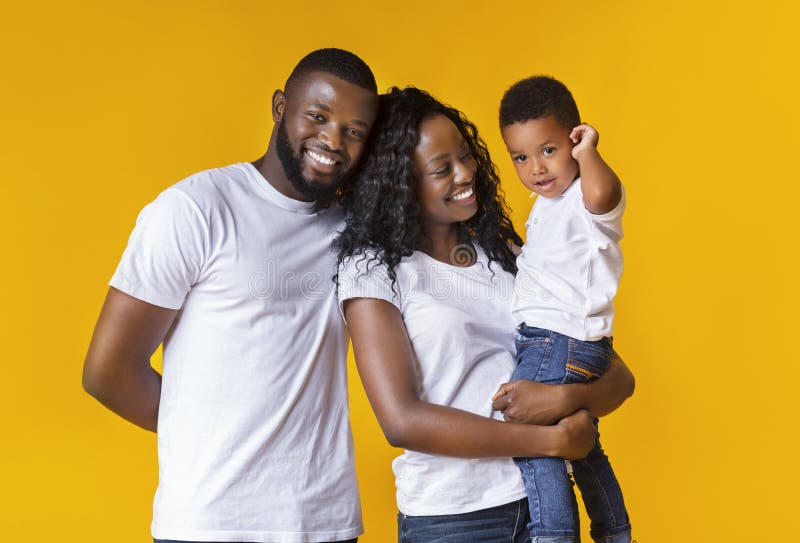 Happy young parents with cute little son over yellow background royalty free stock images Happy young parents with cute little son over yellow background royalty free stock images
