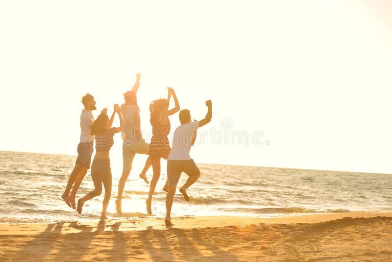 Feliz joven grupo tener divertido blanco correr a saltando sobre el sobre el atardecer.