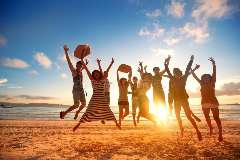 Gruppo di felice giovani di salto in spiaggia il bellissimo tramonto di fine estate.