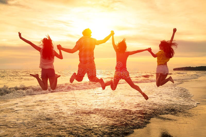 Skupina šťastných mladých lidí skákání na pláži.