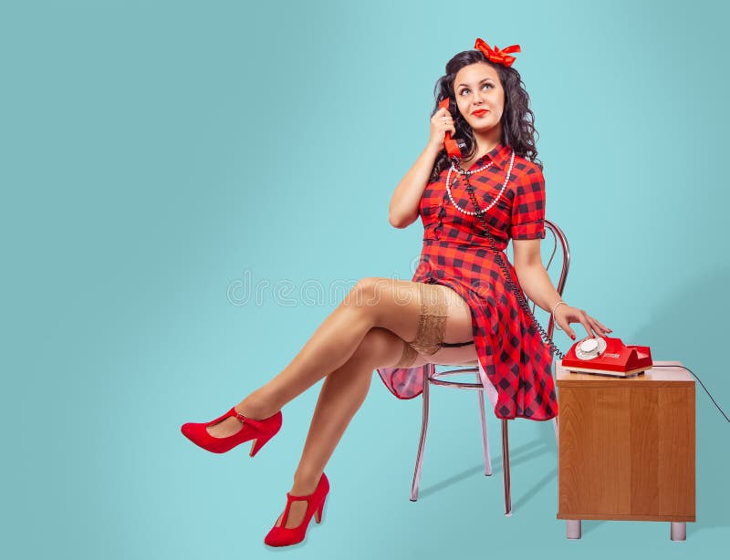 Happy young pinup woman sitting on a chair and talking on phone