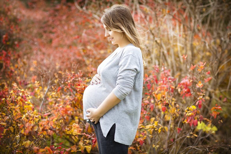 Happy young pregnant woman in autumn park