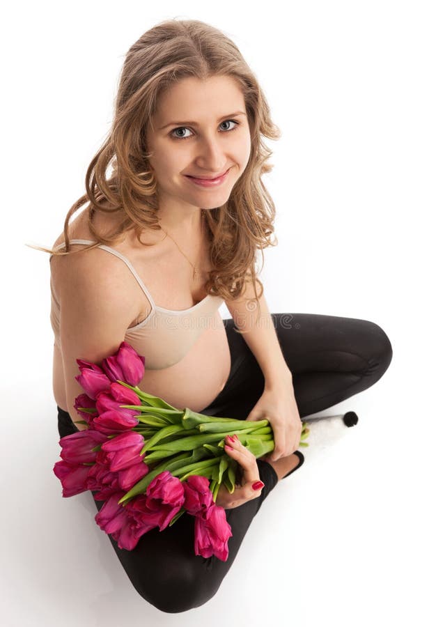 Happy young pregnant woman holding flowers