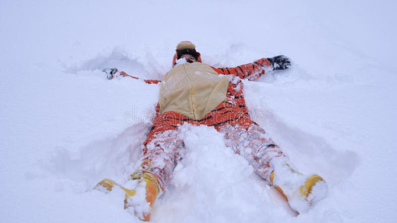 Pretty young woman wearing funny tiger suit lying in snowdrift in winter