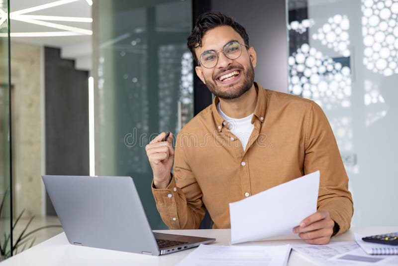 Happy young professional working on a laptop in office stock image