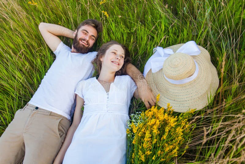 Happy Young Relaxed Couple in Love Laying Down on the Grass Overhead
