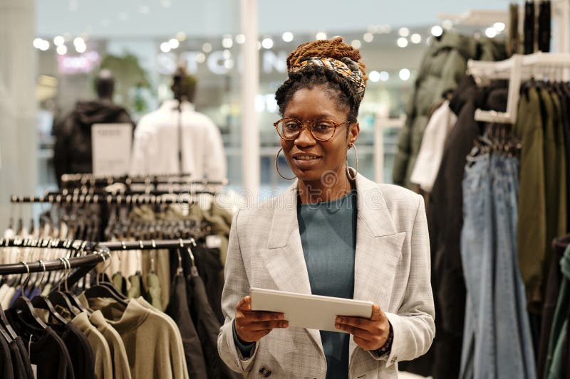 Happy young shop assistant using tablet stock images