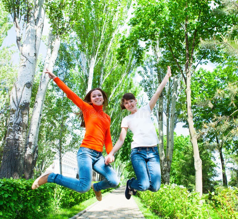 Happy young teen girls jumping it the park