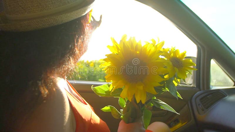 Happy young travel young woman enjoying road trip in summer nature with bouquet of sunflowers. Girl holding arm, puts