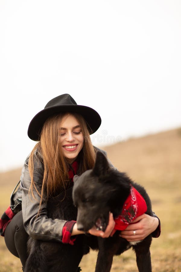 Happy young woman with black hat, plaing with her black dog on the shore of the lake royalty free stock photo Happy young woman with black hat, plaing with her black dog on the shore of the lake royalty free stock photo