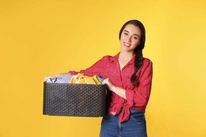 Happy young woman holding basket with clothes