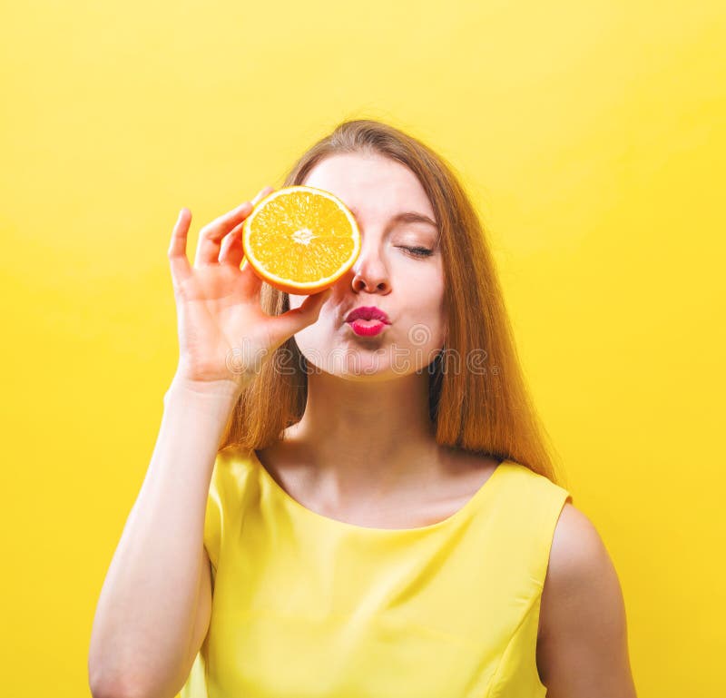 Happy young woman holding a half orange stock photo