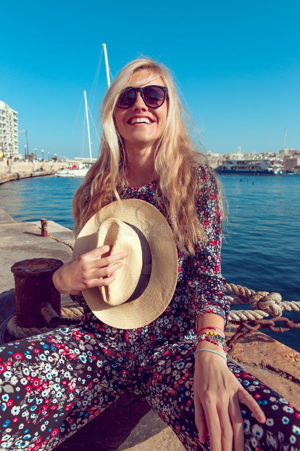 Happy young woman holding hat and toothy smile at sea