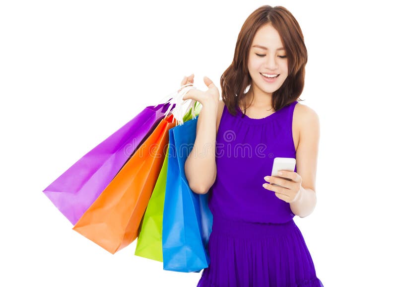 Happy young woman holding shopping bags and mobile phone over white background