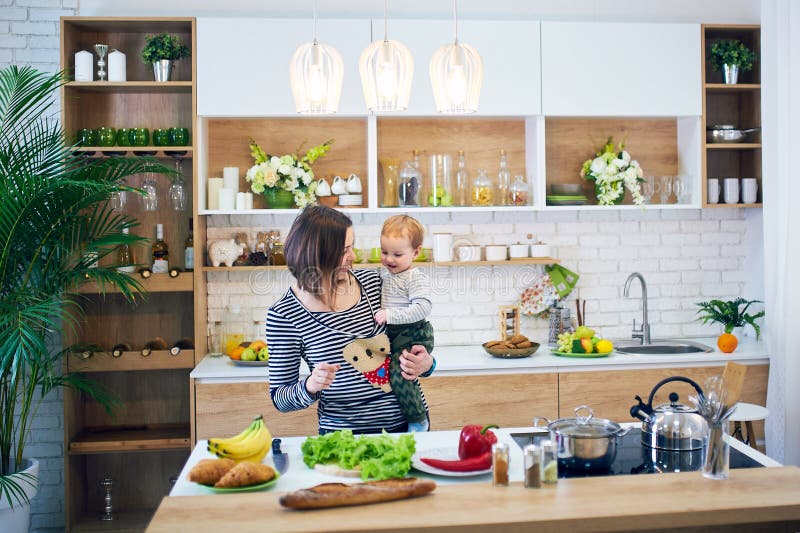 Happy Young Woman Holding a 1 Year Old Child and Cooking Together in