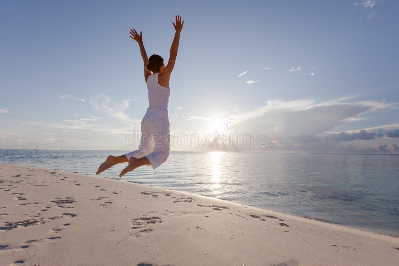 Happy young woman jumping on the beach