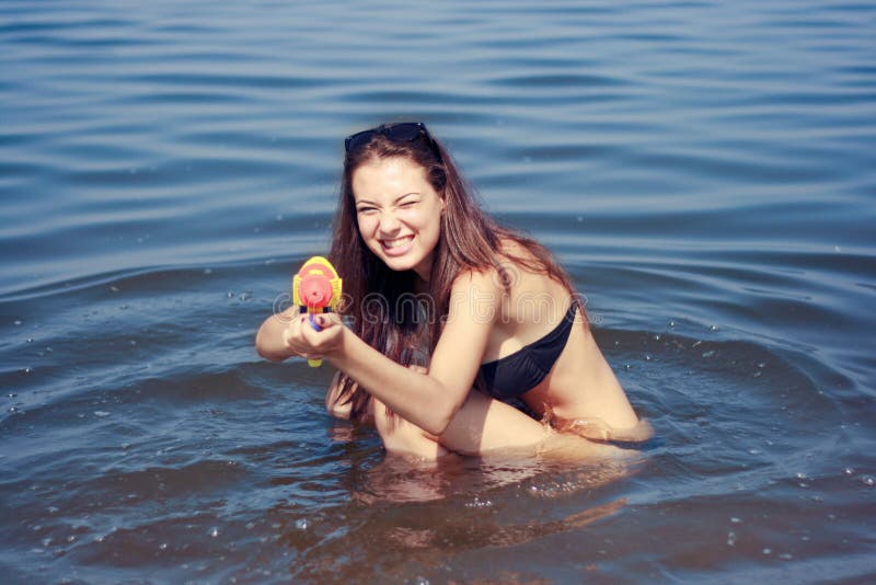 Happy young woman playing with water gun