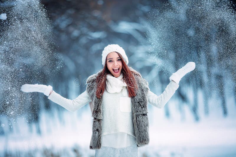 Happy young woman plays with a snow outdoor. Winter day