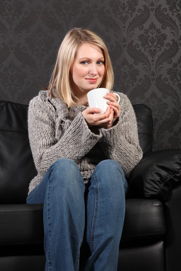 Happy young woman relaxed at home drinking coffee