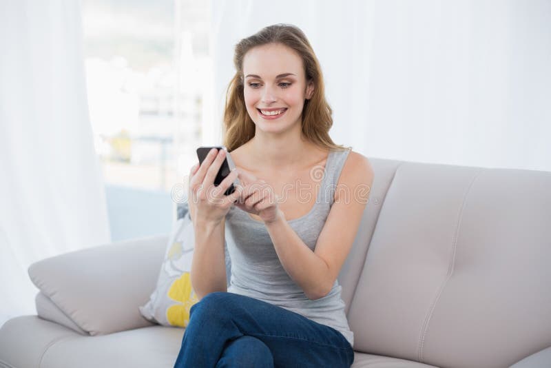 Happy Young Woman Sitting on Couch Using Smartphone Stock Image - Image ...