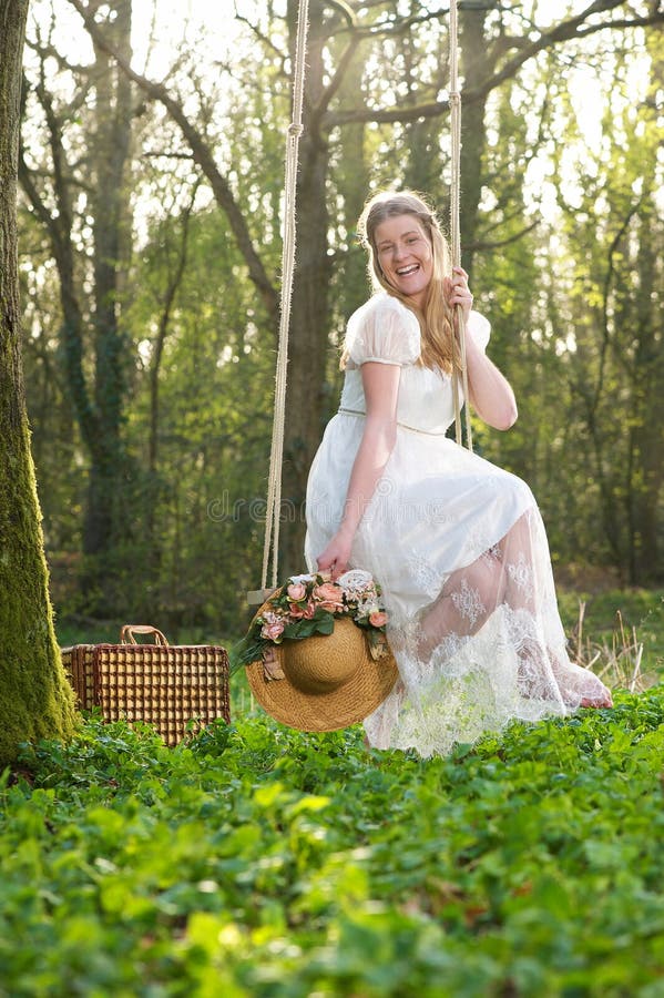 Happy young woman sitting on a swing outdors