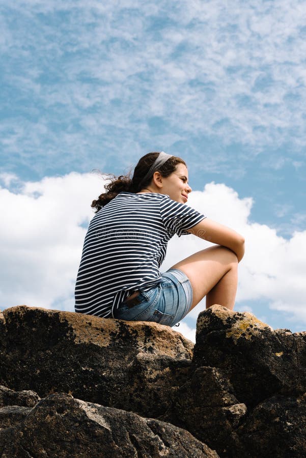 Happy young woman on top of rocks against sky stock photos Happy young woman on top of rocks against sky stock photos