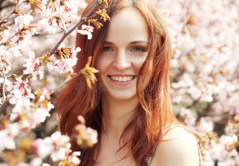 Happy young woman in spring flowers garden