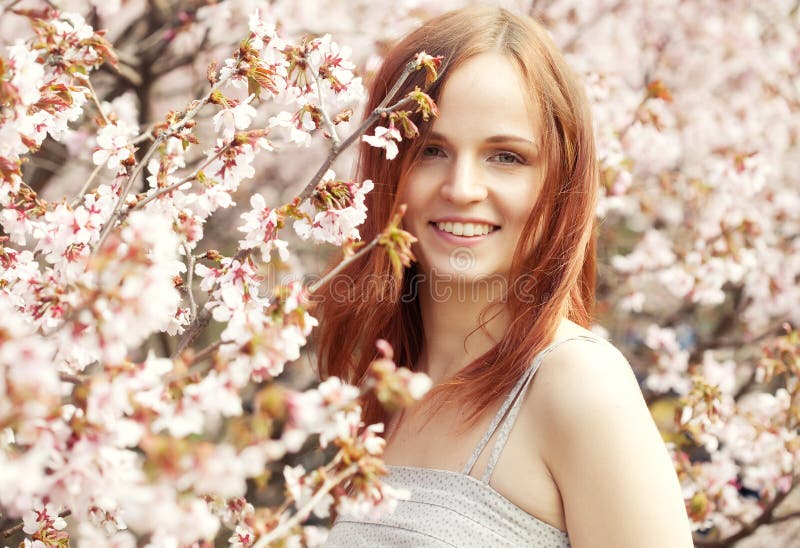 Happy young woman in spring flowers garden