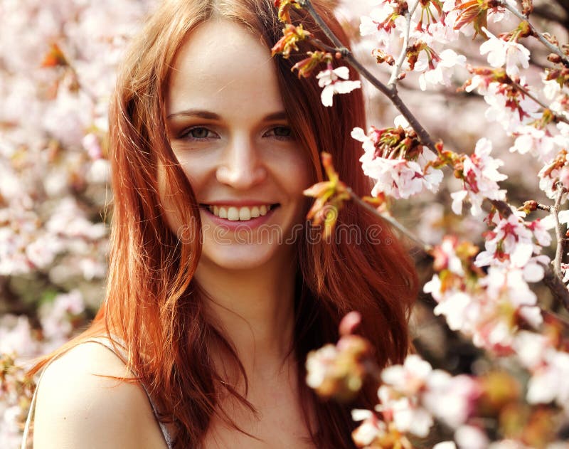 Happy young woman in spring flowers garden