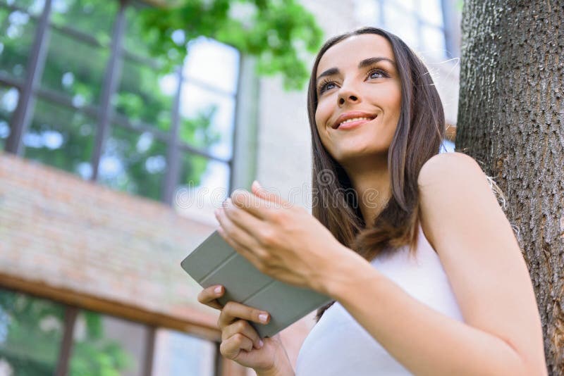 Happy young woman using tablet outside