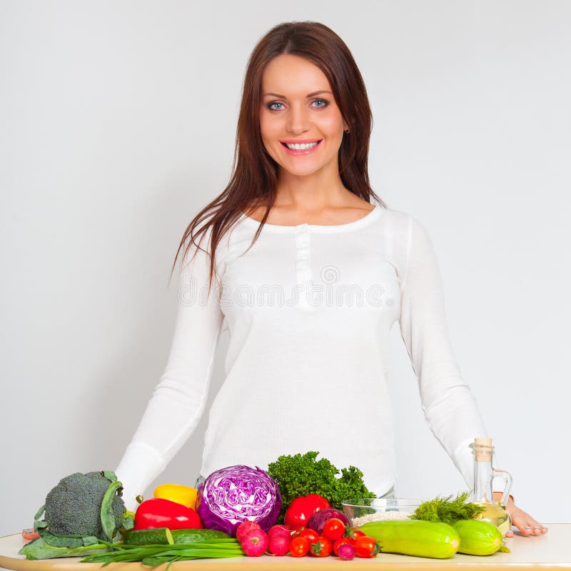Happy young woman with vegetables at kitchen royalty free stock photography