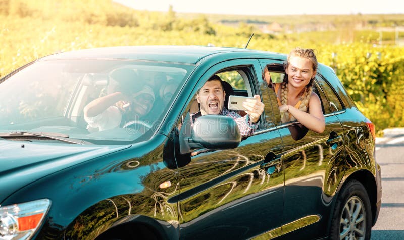 Happy young women and man driver enjoying a summer’s road trip together. Road trip Hangouts royalty free stock photography Happy young women and man driver enjoying a summer’s road trip together. Road trip Hangouts royalty free stock photography