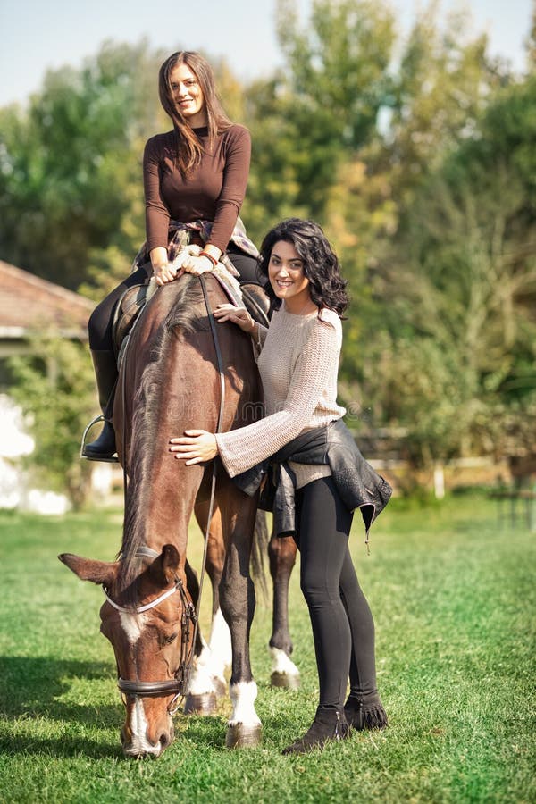 Happy young women standing next horse on ranch stock photography Happy young women standing next horse on ranch stock photography