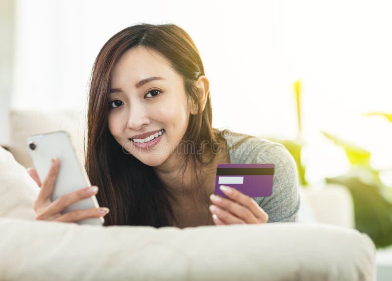 Happy young   women using smartphone shopping online in bed