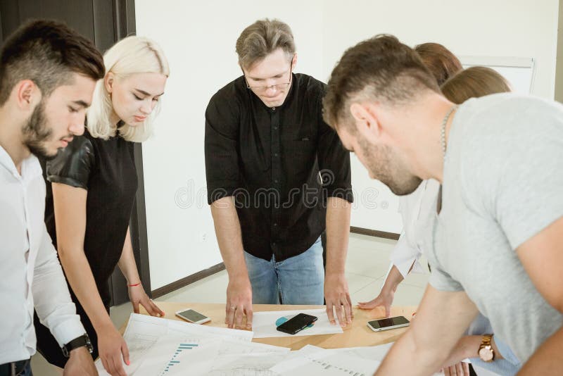 Hard work on the project. All employees and the project manager are standing above the table with documents discussing the project royalty free stock photography Hard work on the project. All employees and the project manager are standing above the table with documents discussing the project royalty free stock photography