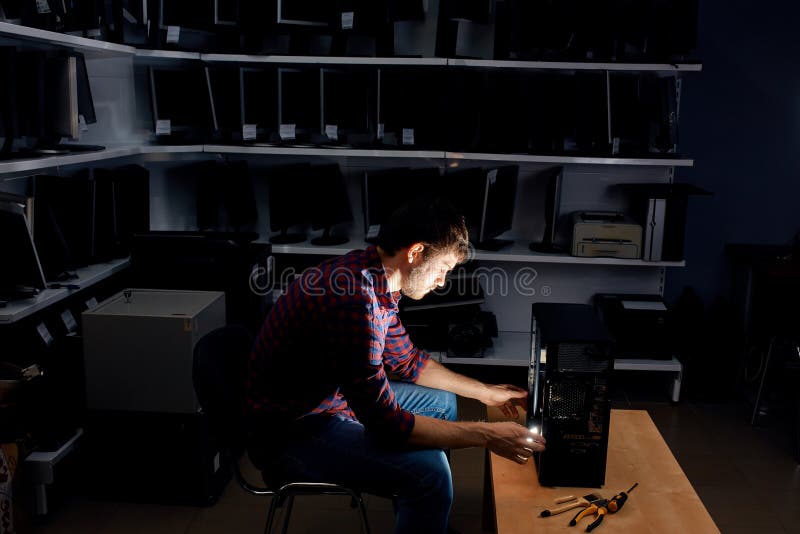 Hardworking IT specialist working with a computer in the dark room at night royalty free stock photo
