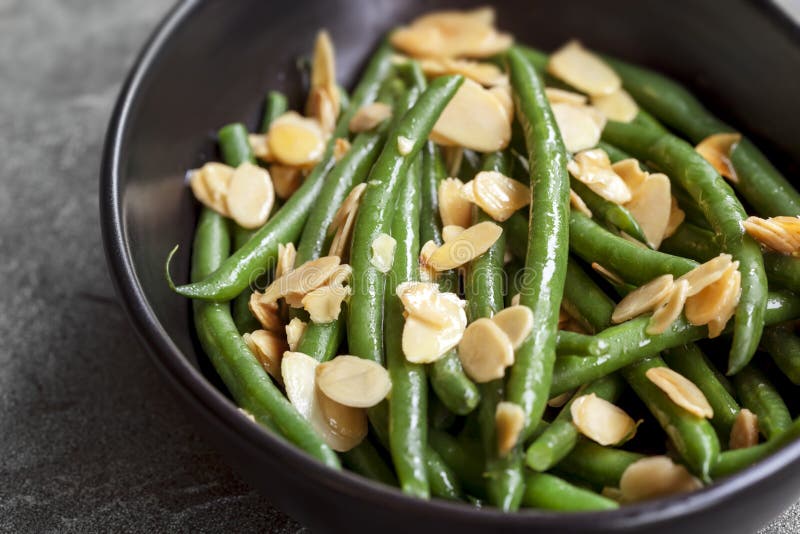 Haricot vert med rostade mandlar i svart bunke royaltyfri fotografi Haricot vert med rostade mandlar i svart bunke royaltyfri fotografi