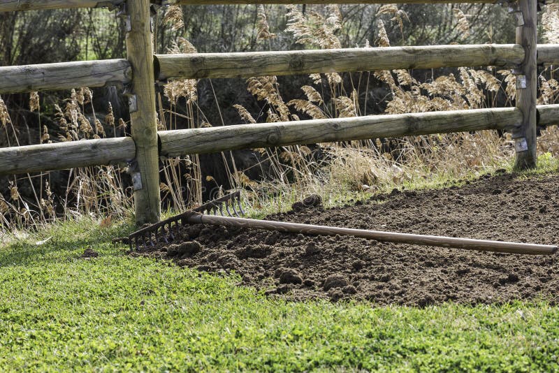 Harken Sie auf Stapel des organischen Düngemittels und des grünen Grases lizenzfreies stockfoto Harken Sie auf Stapel des organischen Düngemittels und des grünen Grases lizenzfreies stockfoto