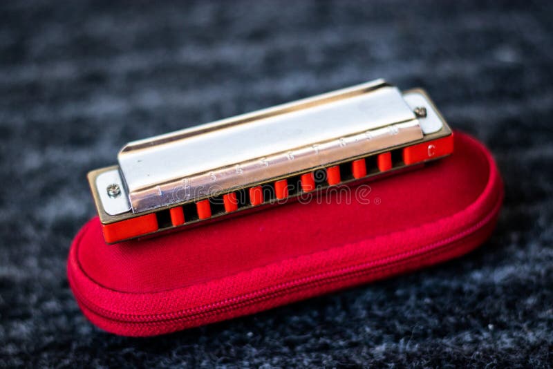 Red harmonica music instrument on top of its case royalty free stock photo